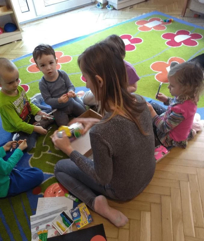 Ciocia z dziećmi w trakcie wspólnej zabawy na dywanie